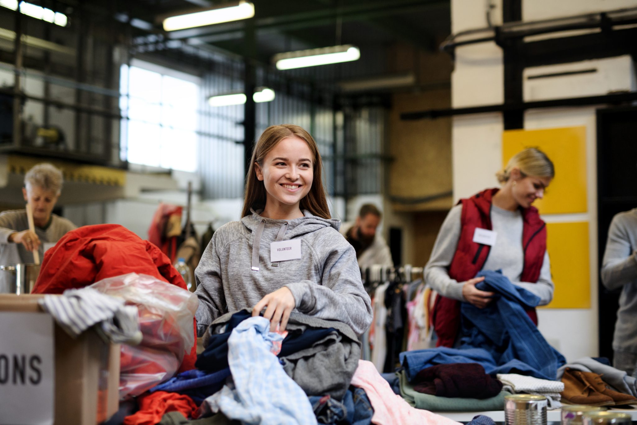 A volunteer smiling while sorting through clothing donations.